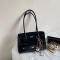 Black patent leather tote bag with silver hardware and dog charm on a white desk - With Pendant / Black