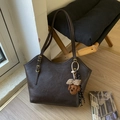 Detail of dark brown tote bag with lychee texture and cute plush puppy charm - With Charm / Coffee
