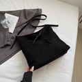 Gros plan d'un sac cabas en daim noir avec détail nœud sur un drap blanc soyeux - Noir