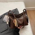 Minimalist dark brown dumpling bag with retro wood bead charm in a lifestyle setting - Coffee (With Bead Pendant)