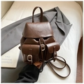 Detail of vintage dark brown faux leather backpack featuring buckled front pockets and grain - Brown