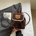 Detail eines braunen Mini-Rucksacks aus Leder mit Spitzenbesatz und Bären-Patch - Kaffeebraun