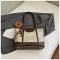 Bruine en groene leren draagtas met donut-pluche bedeltje op grijze blazer - Grijs Met Hanger