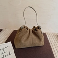 Dettaglio della borsa a secchiello in camoscio marrone con pieghe e manici color crema - Cachi