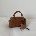 Vue détaillée du sac bowling marron avec breloque ours en peluche sur tissu blanc - Marron avec Pendentif
