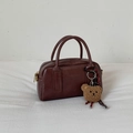 Détail du sac bowling vintage marron foncé avec texture brillante et breloque ours - Café Avec Pendentif