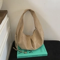 Dettaglio della borsa hobo in camoscio marrone con coulisse e consistenza opaca su un libro - Cachi