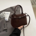 Close-up of matte dark brown handbag texture with silver buckle and leather strap - Brown