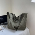 Detail of olive green nylon tote bag with wide shoulder strap in minimalist setting - Army Green