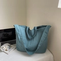 Detail of teal blue crinkled nylon tote bag showing spacious design and wide shoulder strap - Blue