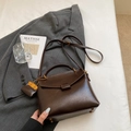 Dettaglio borsa vintage marrone scuro in ecopelle con ciondolo arancione a contrasto - Marrone