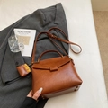 Dettaglio di una borsa vintage marrone in pelle con manico e tracolla regolabile - Cuoio