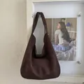 Detail of a dark brown suede tote bag featuring wide shoulder straps and metallic rivets - Brown