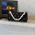Schwarze Zylindertasche mit Perlengriff und verstreuten Perlen auf einer Steinfläche - Schwarz