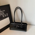 Detailaufnahme der schwarzen Lackleder-Schultertasche mit Zierschnallen und Ziernähten - Schwarz