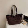 Detalle de un gran bolso tote de ante marrón con correas de cuero y hebillas de metal - café