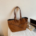 Detalle de bolso tote de ante caramelo con correas de cuero y accesorios de oficina - Marrón