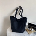 Close-up of black nylon tote bag showing the side white tag and front pocket detail - Black