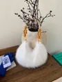 Detail of white faux fur handbag with woven handle and yellow wooden beads on dark wood - White