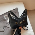 Classic black hobo tote bag with gold metal hardware on casual white bedding - Black