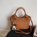 Nahaufnahme der braunen geflochtenen Handtasche mit runden Griffen und Plüsch-Hundeanhänger - Mit Anhänger / Braun