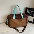 Detail der Reisetasche mit braunem Nylonkörper und hellblau gesteppten Handgriffen - Braun