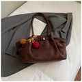 Détail du sac cabas marron mat avec breloque pompon et boucle métallique sur tissu blanc - Café avec Pendentif