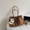 Detailed macro view of brown suede tote bag with metal buckle and plush puppy charm - Yellow Brown (With Charm)