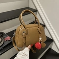 Detail der kamelbraunen Boston-Tasche mit Faltenstruktur und dekorativen Plüsch-Anhängern - Braun mit Anhänger