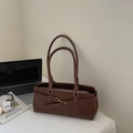 Braune Vintage-Lederschultertasche mit Laptop und silbernen Kopfhörern auf dem Tisch - Braun