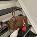 Braune Boston-Tasche mit Plüschkugel-Anhänger vor einem Treppenhintergrund gezeigt - Kaffee Mit Anhänger