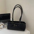 Detail der schwarzen Kunstleder-Schultertasche mit Goldschnalle neben Laptop und Magazin - Schwarz