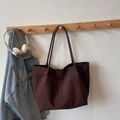 Detail view of the deep brown suede tote bag with slim straps in a lifestyle setting - Coffee No Charm