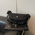 Detail van zwarte nylon crossbody tas met zilveren M-logo en dambord-bedel decoratie - Zwart Met Hanger