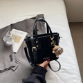 Chic black leather bucket bag with gold lettering and cute brown plush monster charm - Black