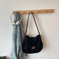 Detail of a black Hobo tote bag with brown leather strap and Banatu brand logo on white wall - No Pendant / Black