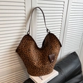 Detailed view of large leopard print suede tote bag with brown leather handles and charm - Coffee Leopard