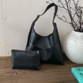 Detalle de conjunto de bolsos hobo de cuero PU negro con textura vintage en mesa de madera - Negro