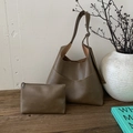Detail of a deep khaki hobo tote set including a matching zipper pouch on a wooden desk - Tan