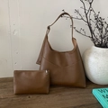 Primer plano de bolso tote de cuero marrón con estuche a juego sobre superficie de madera - Marrón