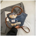 Detail der blauen Denim-Schultertasche mit braunem Ledergriff und süßem Bären-Anhänger - Braun mit Anhänger