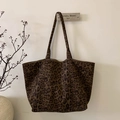 Detail van luipaardprint suède shopper hangend aan een witte muur met minimalistisch decor - Koffie Grote Luipaardprint