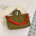 Close-up of olive green tote bag featuring a red braided rope strap on a flat lay set - Green