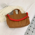 Detail of caramel tote bag with thick red and white woven rope handles on a soft surface - Brown