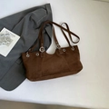 Dettaglio della borsa tote in pelle scamosciata marrone con occhielli e fibbia regolabile - Marrone