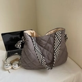 Detail of dark grey quilted tote bag with black and white striped straps and laptop - Gray