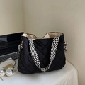Detail of black quilted tote bag featuring striped handles and decorative side ribbon bows - Black