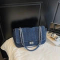 Dettaglio ravvicinato della borsa in denim blu con motivi trapuntati e chiusura argento - Blu scuro