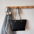 Detail of the black quilted tote bag hanging with chain strap and brand logo - Black without Pendant