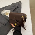 Detail of a deep brown crossbody bag with gold lettering and a plush monster charm - Coffee without Pendant